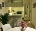modern kitchen with a counter, two stools, plant, flowers in a vase, and framed pictures on the wall