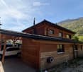 wooden exterior, car parked under carport, mountains in the background