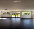empty room, large windows, sliding glass doors, dark wooden floor, white walls, ceiling lights