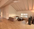 Bright living room with wooden floors, exposed wooden beams, large window, sofa, coffee table, and a small stool.