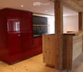 Modern kitchen with red cabinets, wooden island, and sleek sink area.