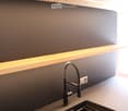 Modern kitchen sink area with a sleek, dark countertop, a contemporary faucet, and built-in LED lighting above.
