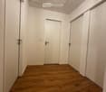 Empty hallway with wooden flooring, white walls, and two closed doors.