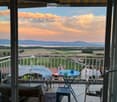 Balcony with scenic view of mountains and countryside, furnished with a small table, chairs, and a stool.