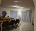 Dining room with a wooden dining table, six chairs, a mirror, and a small shelf with decorative items.