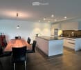 Modern kitchen with white cabinets, a central island, a dining table with chairs, and various appliances.