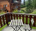 Balcony with wooden railing, concrete floor, and a small table with two chairs.