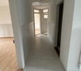 Empty hallway with white tiles, wooden floor, white walls, white doors, ceiling lights