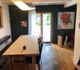 Dining area with wooden table, chairs, bench, artwork, and sculptures.
