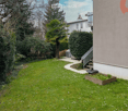 Well-maintained garden with a lawn, small raised bed, and a pathway leading to a house entrance.