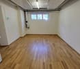 Empty room with wooden flooring, white walls, and a small window at the far end. No furniture or equipment is present.