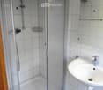 Modern bathroom with a glass-enclosed shower stall, a white sink with a chrome faucet, and a mirror above the sink.