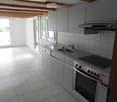 Modern kitchen with grey cabinets, stainless steel appliances, and a tiled backsplash. Features a sink, oven, dishwasher, and range hood.