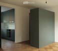 Modern kitchen with grey cabinets, a sink, a faucet, and an oven, set against light-colored walls and wooden flooring.