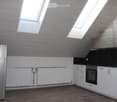 Modern kitchen with white cabinets, stainless steel appliances, wooden flooring, and skylight windows.