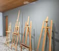 Empty room with grey walls, speckled tile floor, and wooden easels arranged in rows.