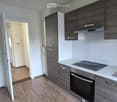 Modern kitchen with dark wood cabinets, stainless steel appliances, and wooden flooring.