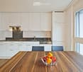 Modern kitchen with white cabinets, stainless steel appliances, granite countertops, and a wooden dining table with chairs.