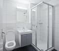 Modern bathroom with white tiles, a toilet, a sink with a mirror, and a glass-enclosed shower stall.