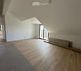 Empty room with wooden flooring, white walls, and a large window leading to a balcony.