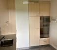 Modern kitchen with light wood cabinets, stainless steel oven, granite countertop, and tiled floor.