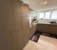 Modern kitchen with light-colored cabinets, stainless steel appliances, and a light wooden floor. The kitchen features a coffee maker, sink, and various small appliances on the counter.
