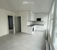 Empty kitchen with white cabinets, tiled floor, and large windows. No furniture or appliances are present.