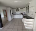 Modern kitchen with white cabinets, tiled floor, black countertop, and stainless steel sink and faucet.