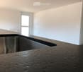 large stainless steel sink, granite countertop, white walls, large windows