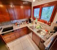 The kitchen features wooden cabinets, a granite countertop, and stainless steel appliances including a sink and oven. Various kitchen items and utensils are placed on the counter.