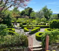 Garden / Outdoor Area. Well-maintained garden with neatly trimmed hedges, gravel pathways, and seating areas including tables and chairs.