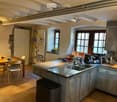 Kitchen. Bright kitchen with exposed wooden beams, large windows, marble countertops, and stainless steel appliances. Includes a dining area with a wooden table and chairs.