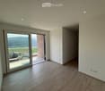 Empty room with wooden flooring, white walls, recessed lighting, and a large sliding glass door leading to a balcony with a scenic view.