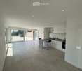 Modern kitchen with white cabinets, granite countertop, bar stool, and large sliding glass doors leading to a patio.