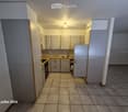 Empty kitchen with light-colored cabinets, tiled floor, and basic appliances like a sink and stove, but no furniture or personal items.