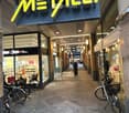 Shop entrance, signboard, bicycles parked, pathway, shop windows, people walking