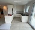 Modern kitchen with white cabinets, a central island, and a black countertop. Features include a sink with a modern faucet, an oven, and a large window providing natural light.