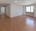 Empty room with wooden flooring, white walls, and large windows with radiators underneath. No furniture or equipment present.