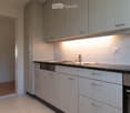 Modern kitchen with white cabinets, granite countertop, stainless steel sink, and built-in appliances including an oven and dishwasher.