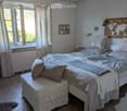 Cozy bedroom with a large bed, pillows, blanket, nightstand, world map on the wall, picture frame, and curtains on the windows.