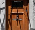Wooden door with a small window and decorative metal handle, set in a white textured wall.
