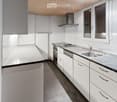 Modern kitchen with white cabinets, stainless steel appliances, and a black countertop. Features include a sink, faucet, oven, dishwasher, and a range hood.