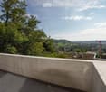 Roof terrace with a low concrete wall, overlooking a cityscape with trees and buildings.