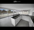 Modern kitchen with white cabinets, black countertops, and large windows offering a view of the surrounding area.