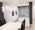 Modern kitchen and dining area with white cabinets, a central island, pendant lights, and a dining table with black chairs.