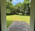 View from a porch onto a grassy yard with trees and a stone pathway leading to the yard.