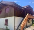 Two-story wooden house with a balcony, wooden shutters, and a staircase leading to the upper level.