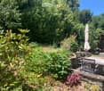 A well-maintained garden with a patio area, outdoor furniture, and lush greenery.