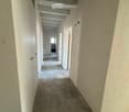 Empty hallway with concrete floors, white walls, and multiple doors leading to other rooms.