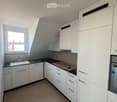 Empty kitchen with white cabinets, black countertops, and a window. No appliances or furniture are present.